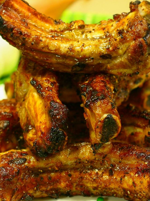 Stack of baked baby back rib pieces with garnished green onion sprig.