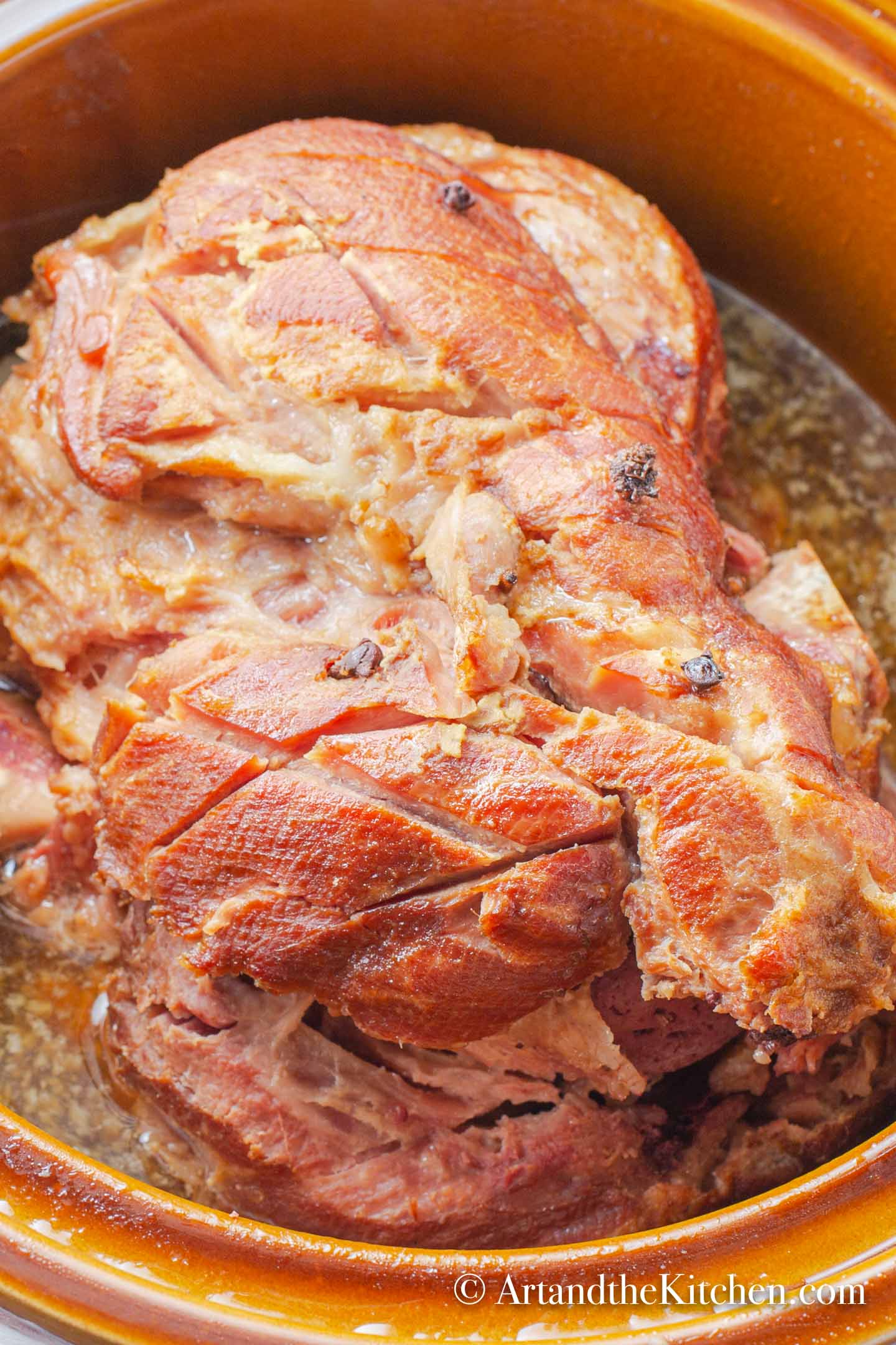 Whole bone-in ham cooking in slow cooker.