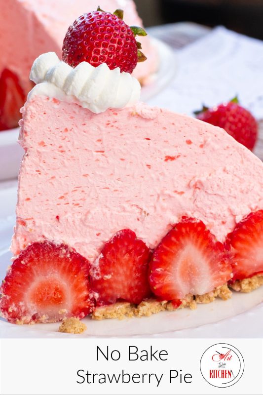 A slice of fluffy no bake strawberry pie, fresh strawberries on white plate with whole pie with slice cut out in background.