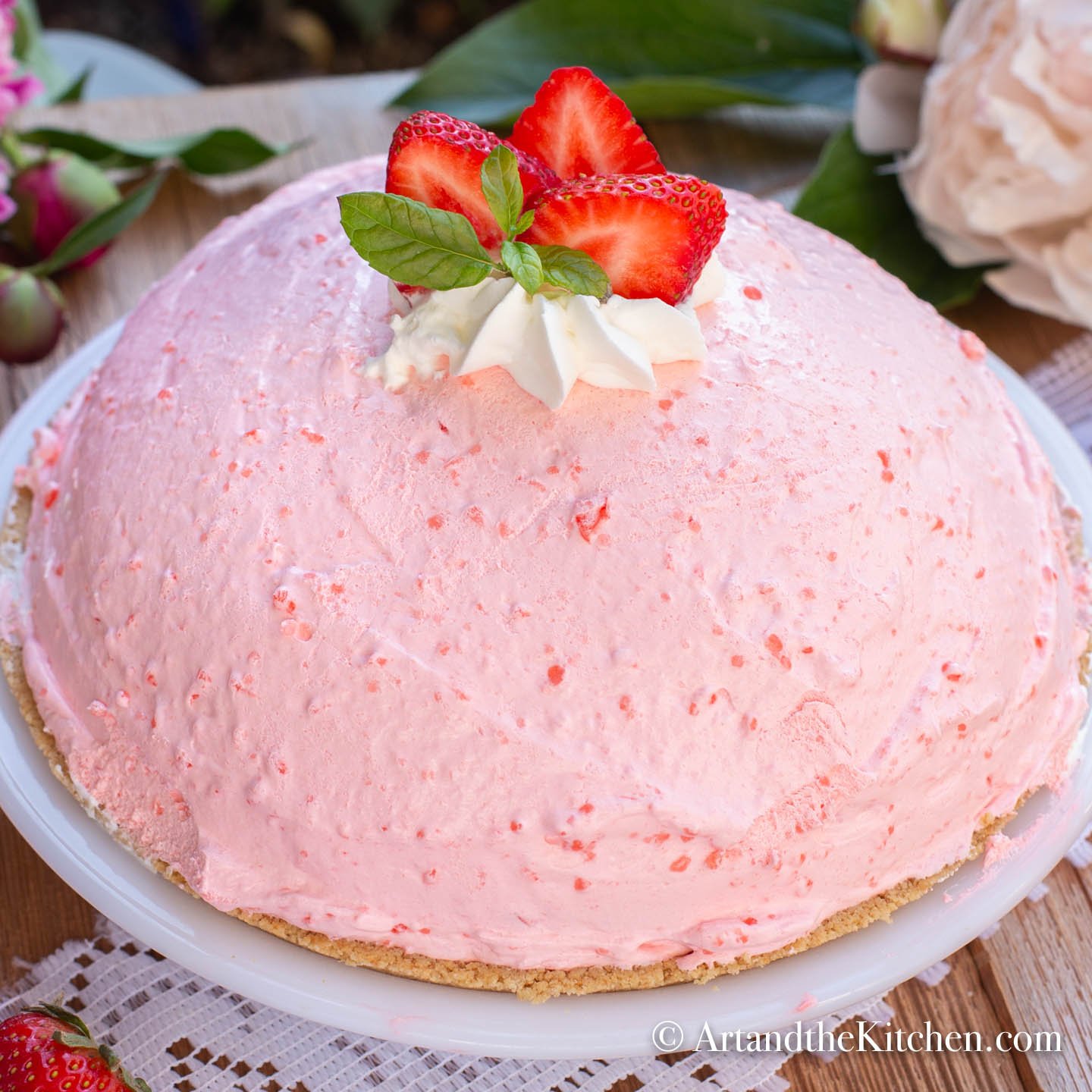 A whole high, fluffy no bake strawberry pie garnished with fresh strawberries, mint and dollop of whipping cream.