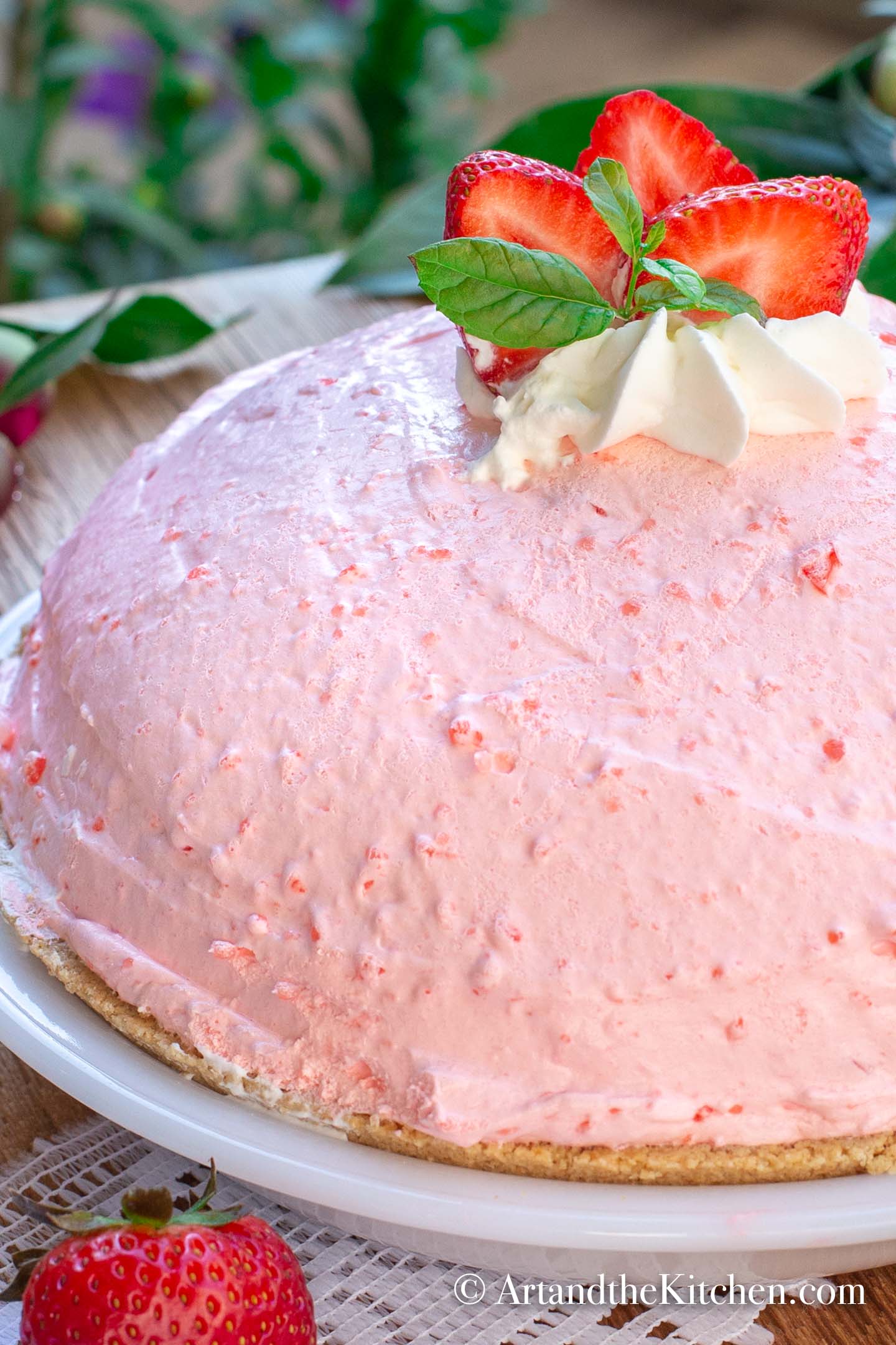 A whole high, fluffy no bake strawberry pie garnished with fresh strawberries, mint and dollop of whipping cream.