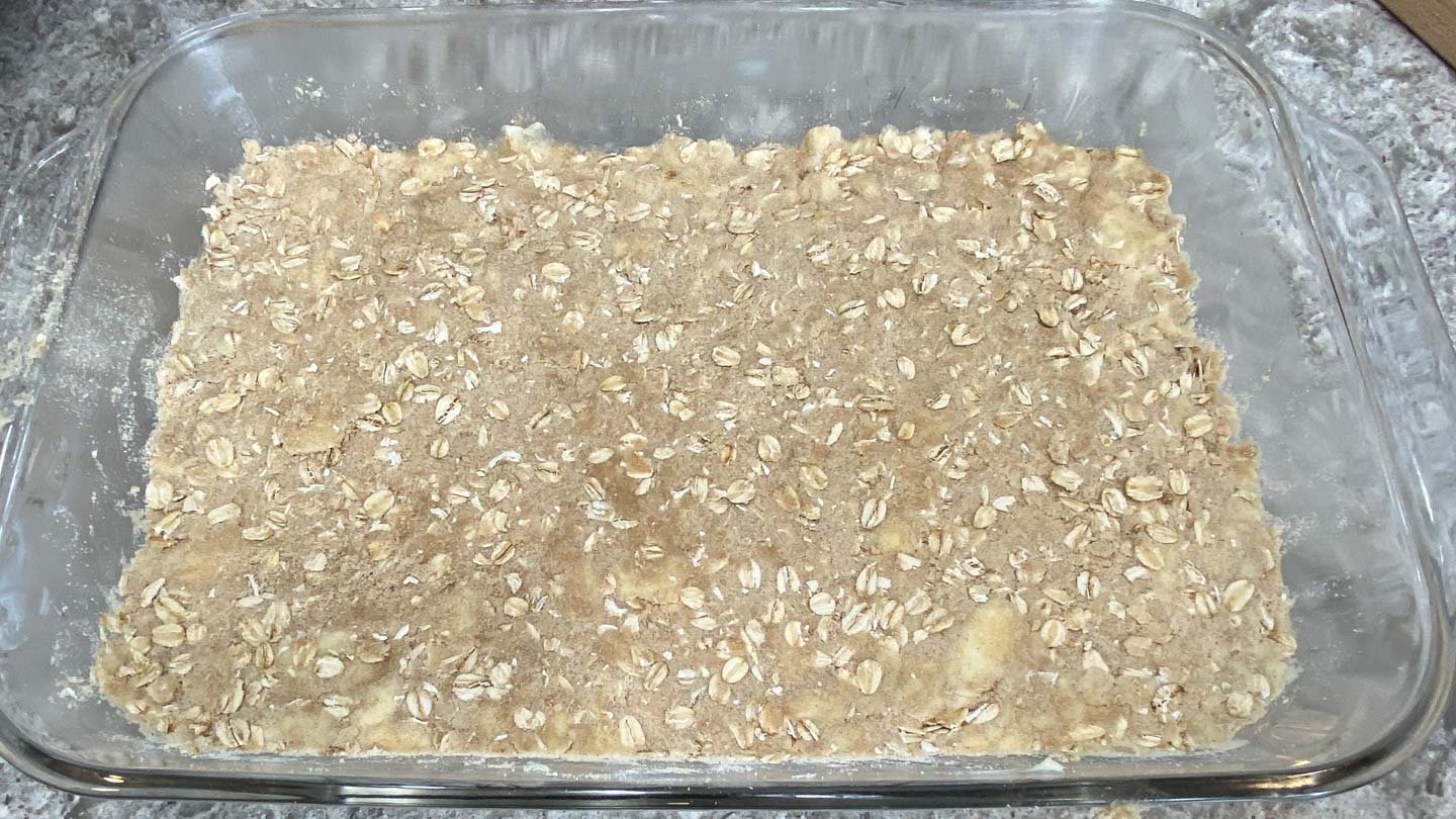 Oatmeal butter crumb mixture pressed into glass baking pan.