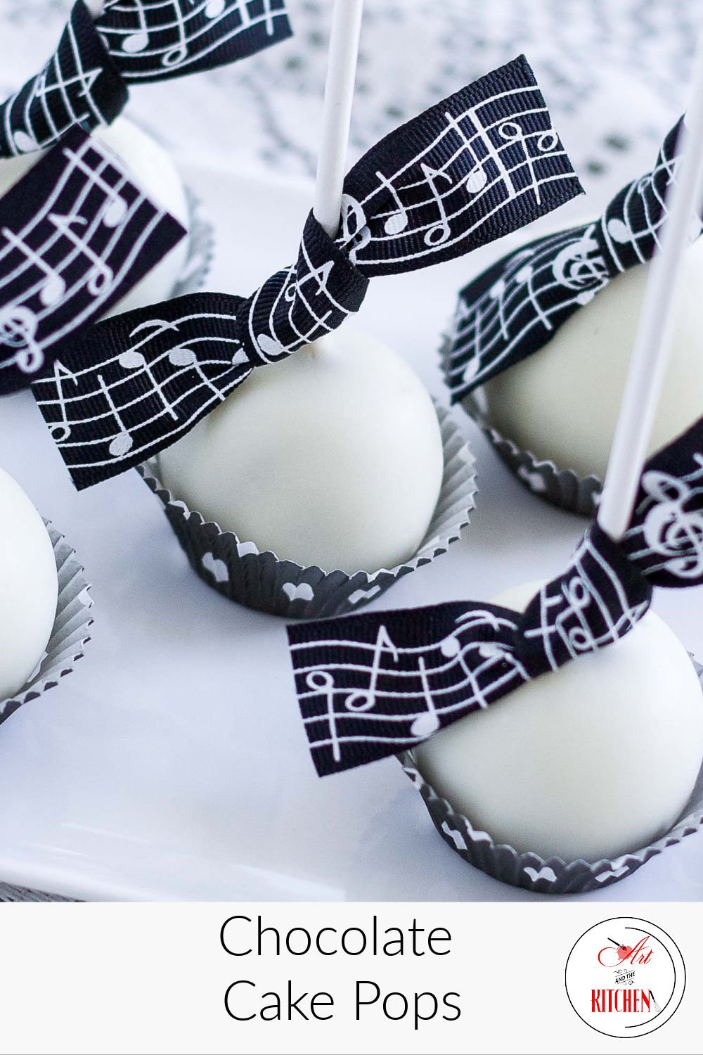White chocolate coated cake pops with music themed ribbon tied to stick.