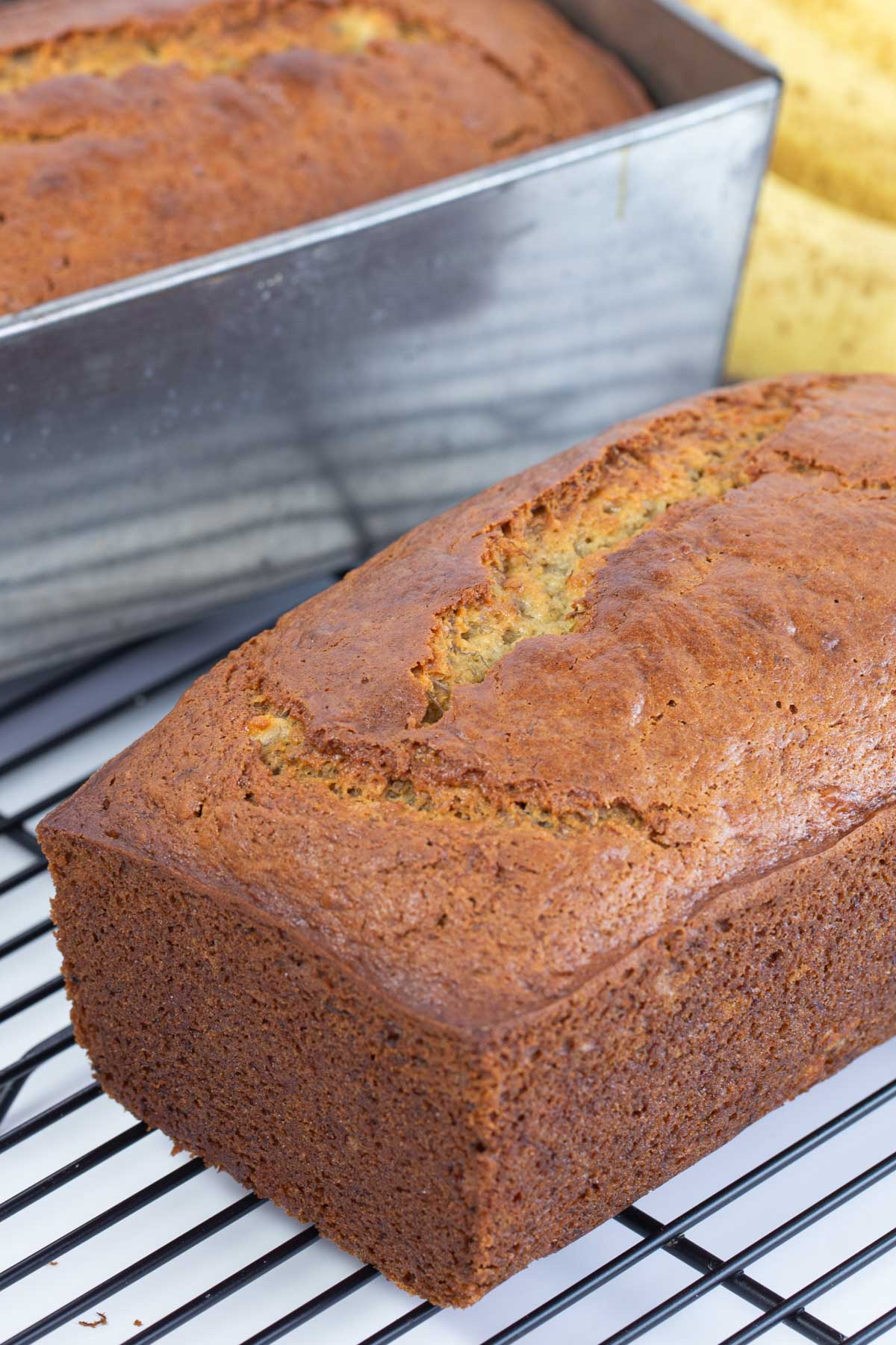 Two whole loaves of banana bread on black wire rack.