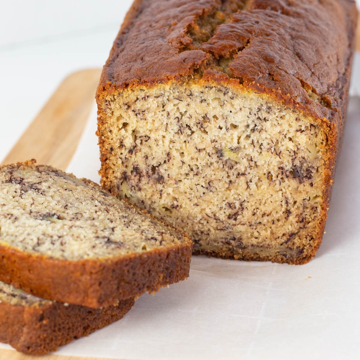 Whole loaf of banana bread with two cut slices.