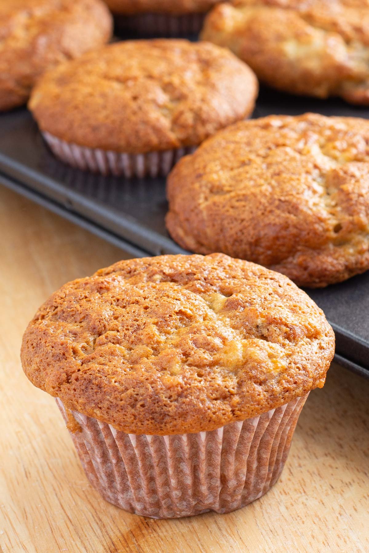 Banana muffin with pan of muffins in background.