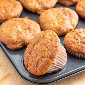 Muffin tin full of banana muffins with golden brown crisp tops.