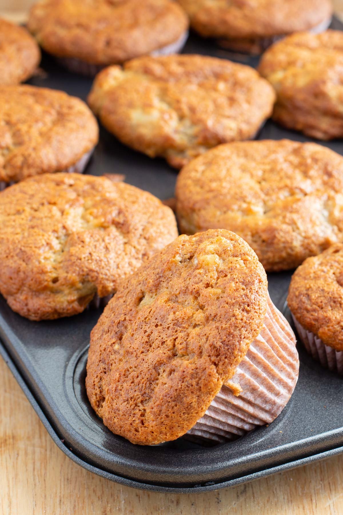 Muffin tin full of banana muffins with golden brown crisp tops.