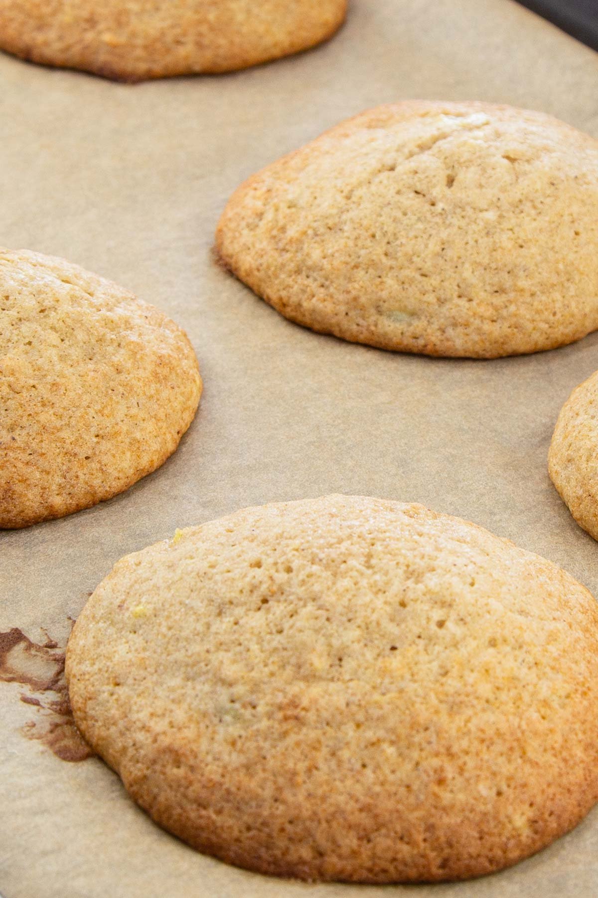 Fluffy banana cookies on brown parchment lined baking sheet.