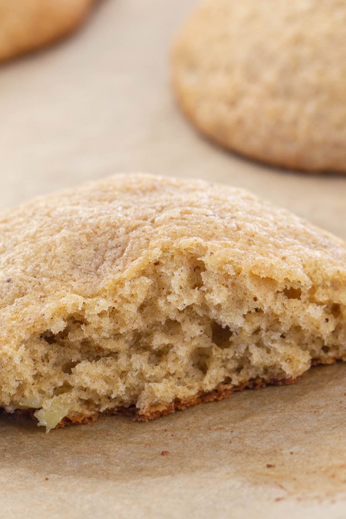 Soft banana cookie with bite out of it on brown parchment paper.