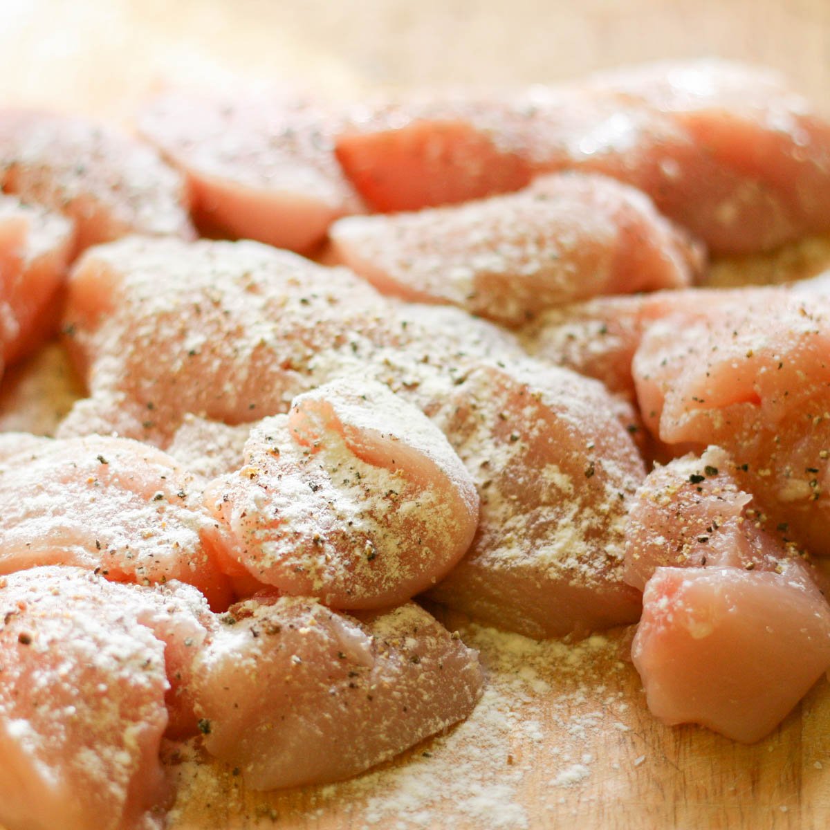 Chicken breasts chopped into bite sized pieces sprinkled with flour.