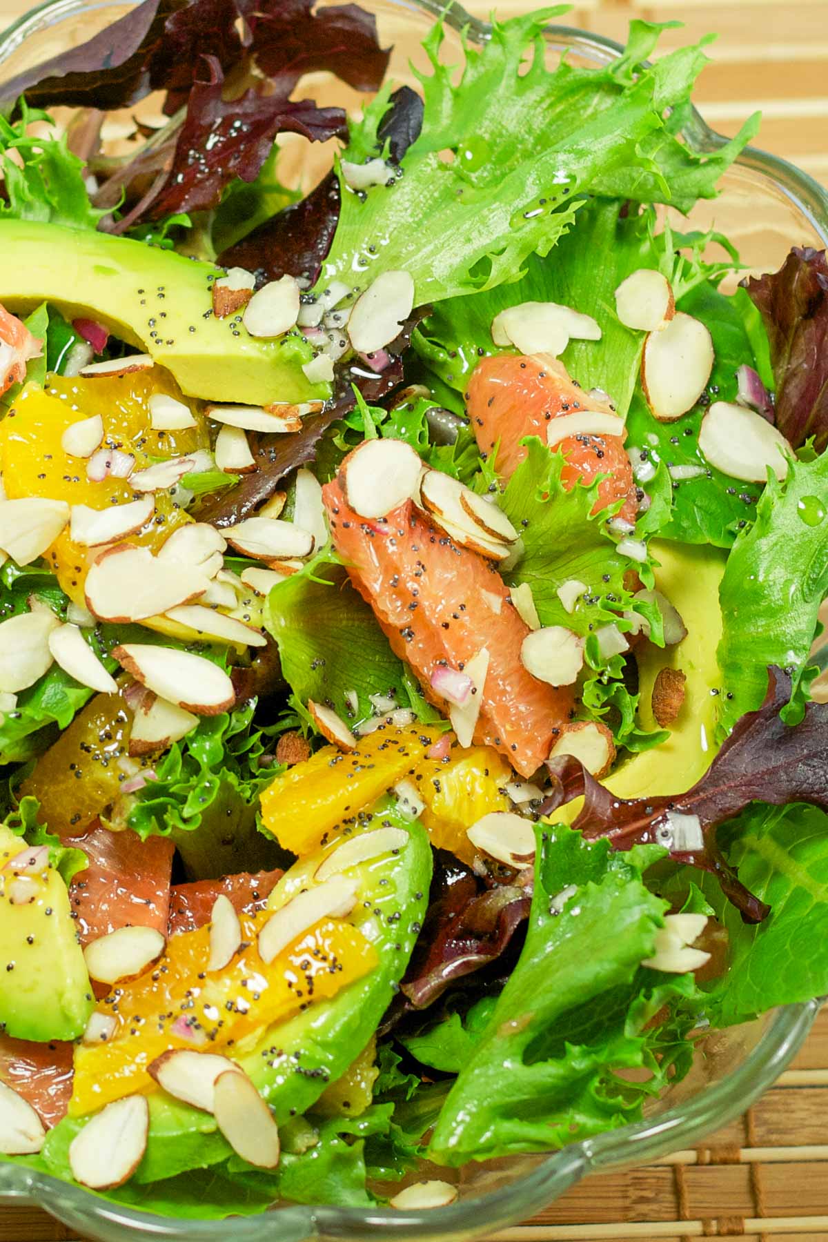 A bowl of fresh salad greens with avocado, grapefruit, and oranges. Sprinkled with almond slivers and poppyseed dressing.