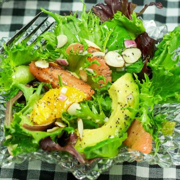 A bowl of fresh salad greens with avocado, grapefruit, and oranges. Sprinkled with almond slivers and poppyseed dressing.