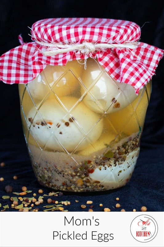 Glass jar of pickled eggs with decorative red checkered cloth lid.