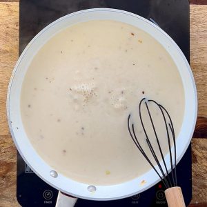 Cream sauce simmering in white skillet.