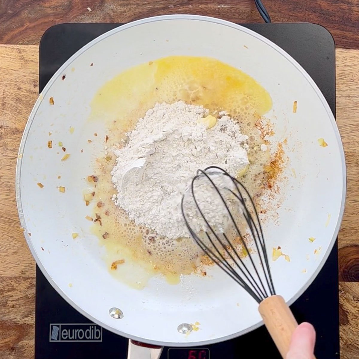 Flour whisked into melted butter in white skillet.