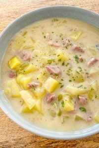 Creamy soup of potatoes and ham in a blue bowl.