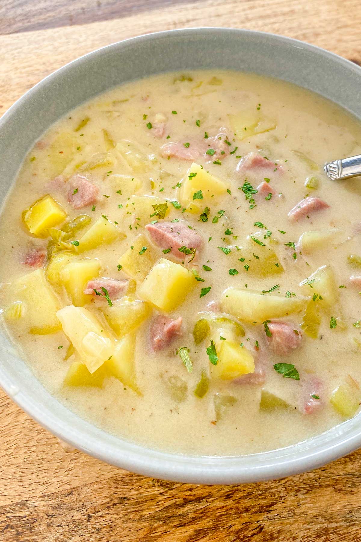 Creamy soup made with ham and potatoes in a blue bowl.