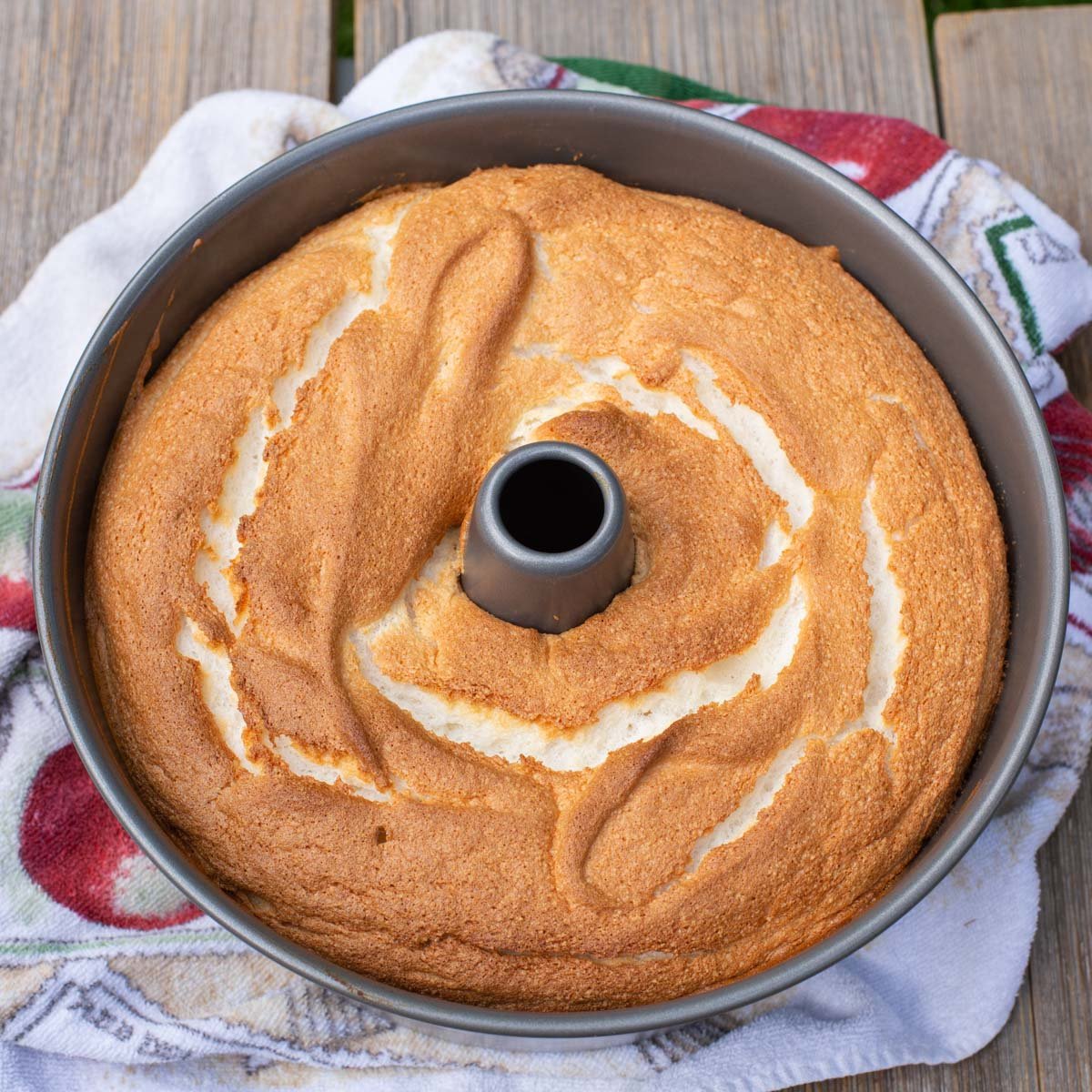 Baked angel food cake cooling in metal tube pan.