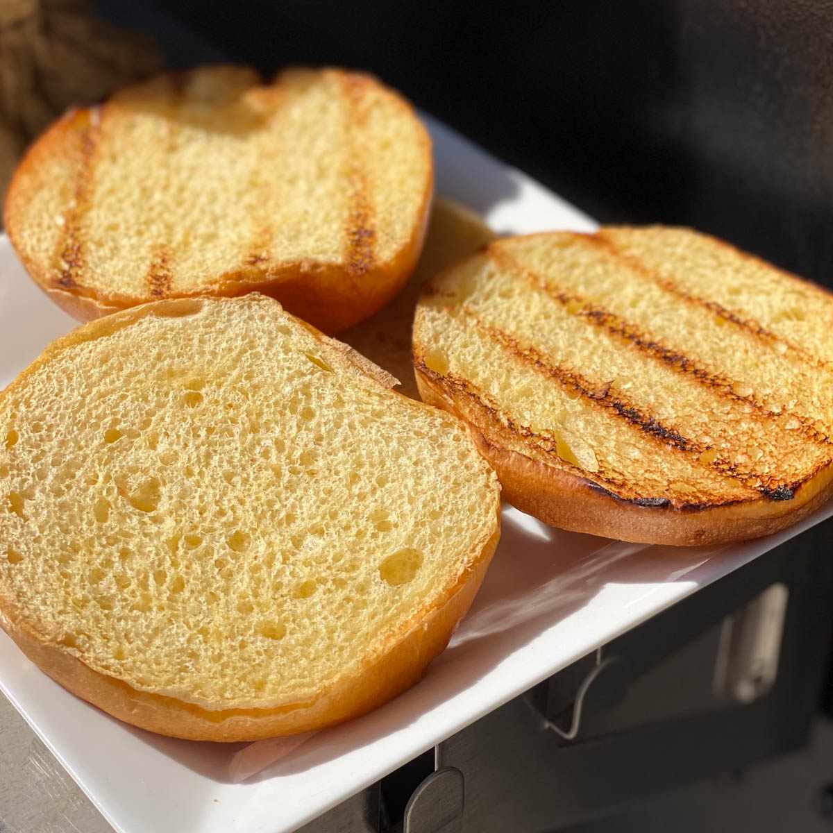 Grill toasted brioche buns on white plate.