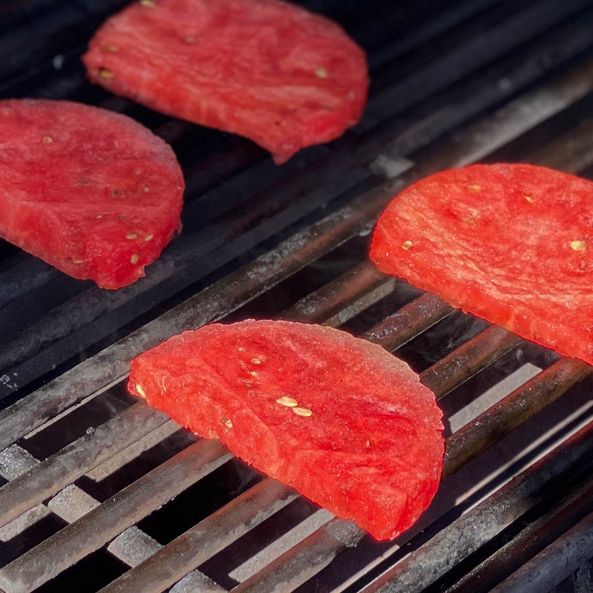 Slices of watermelon grilling on barbecue.