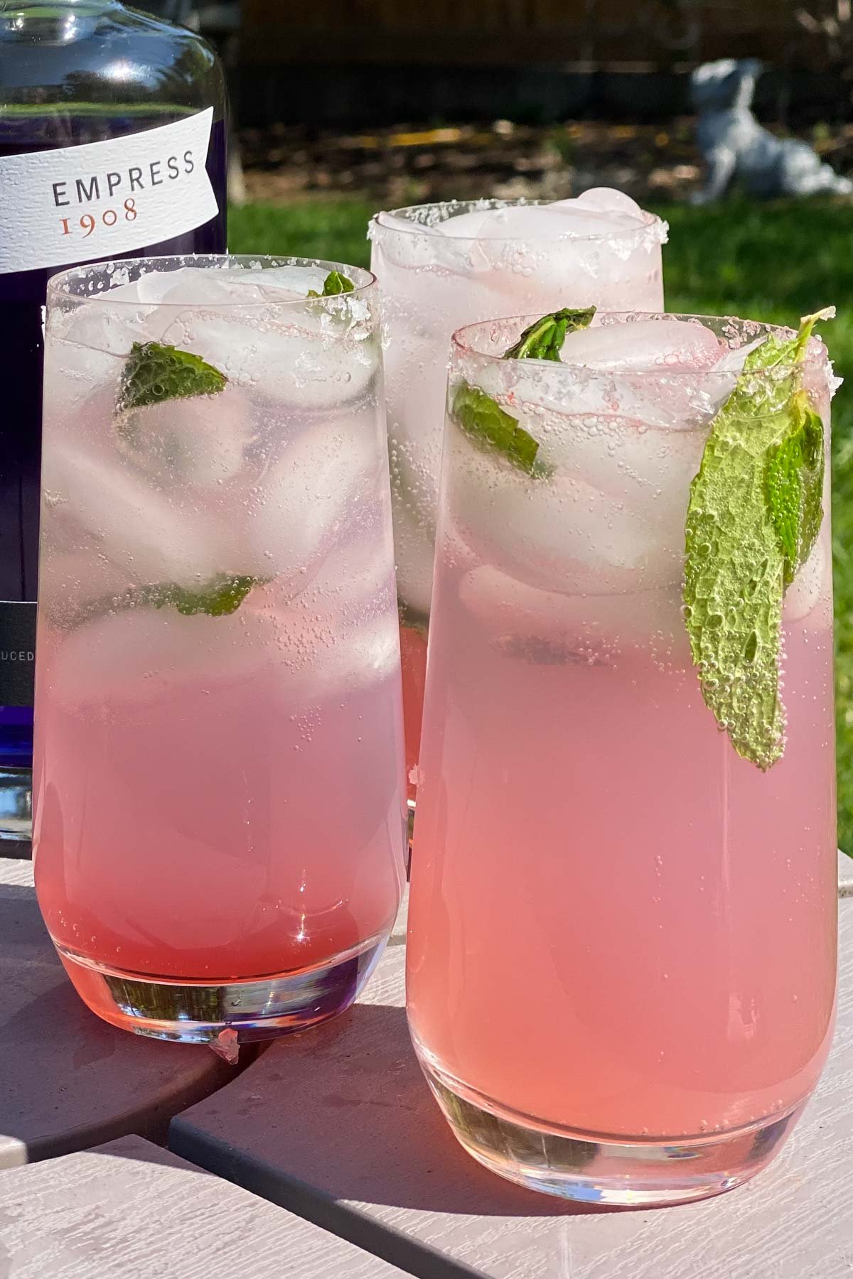 Three tall glasses of gin cocktail garnished with mint.