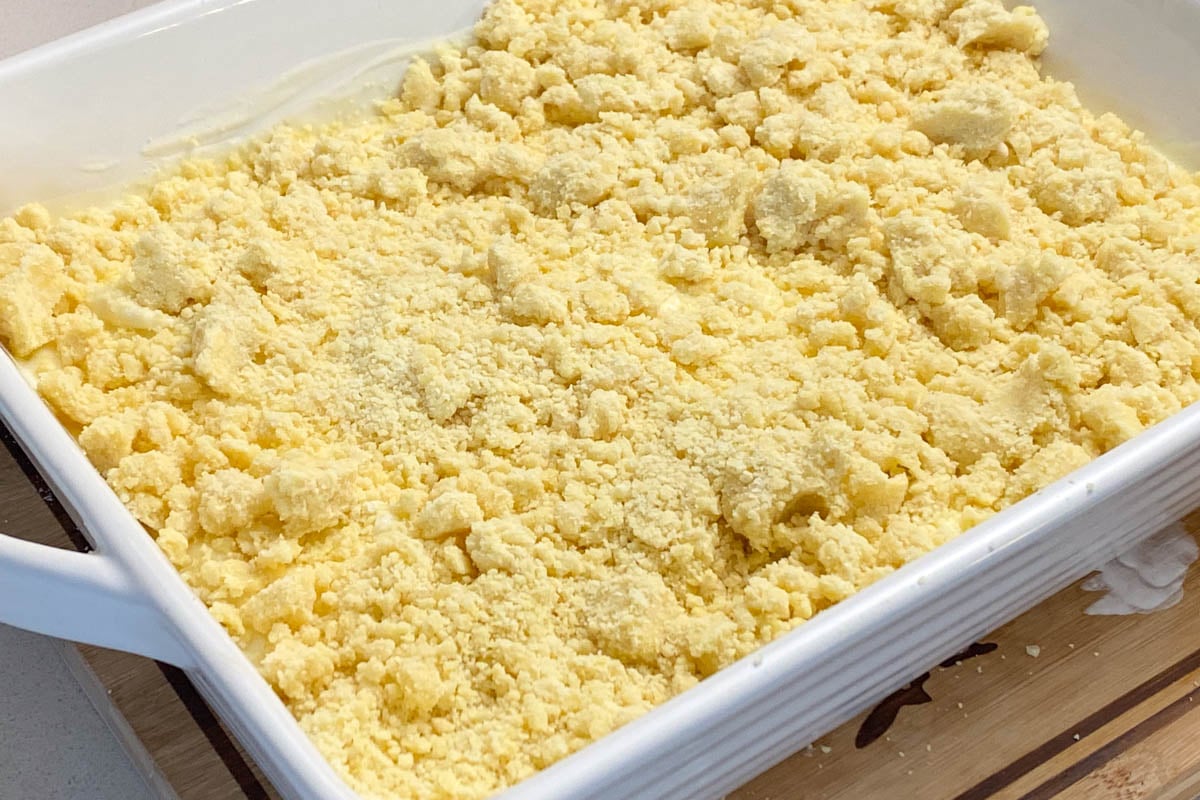 Crumbled lemon cake mix in white cake pan.