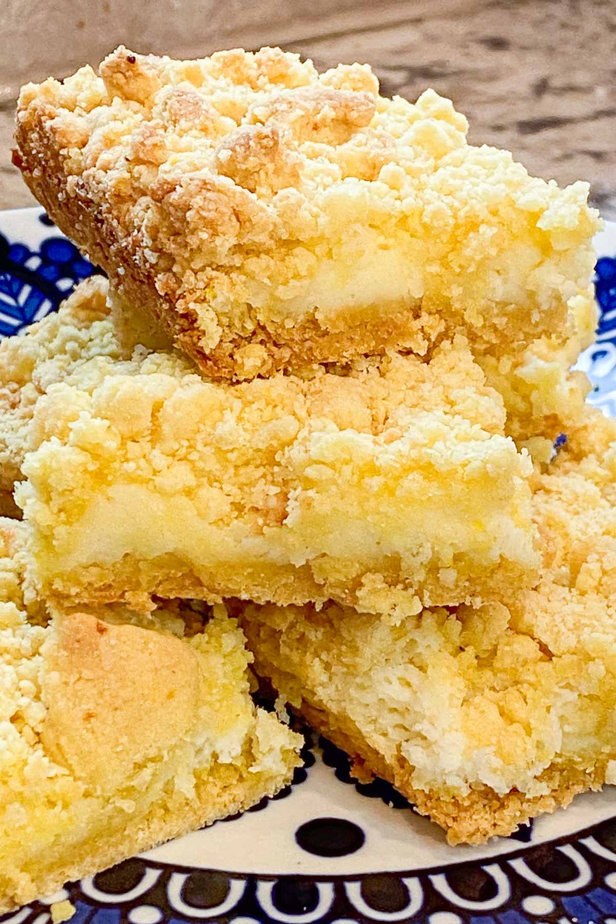 Stack of lemon bars with crumbly topping on decorative blue plate.