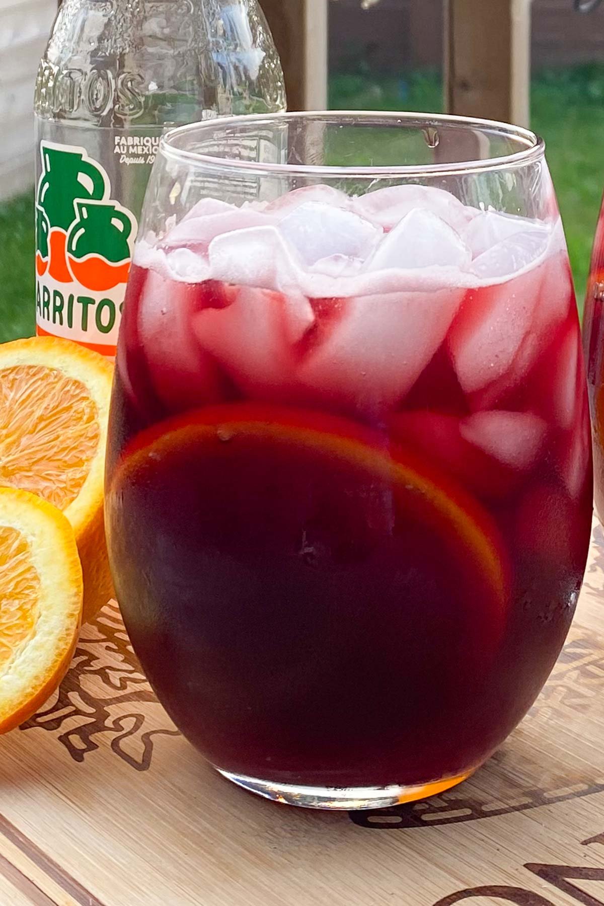 Glasses of red wine with orange slice and ice cubes.