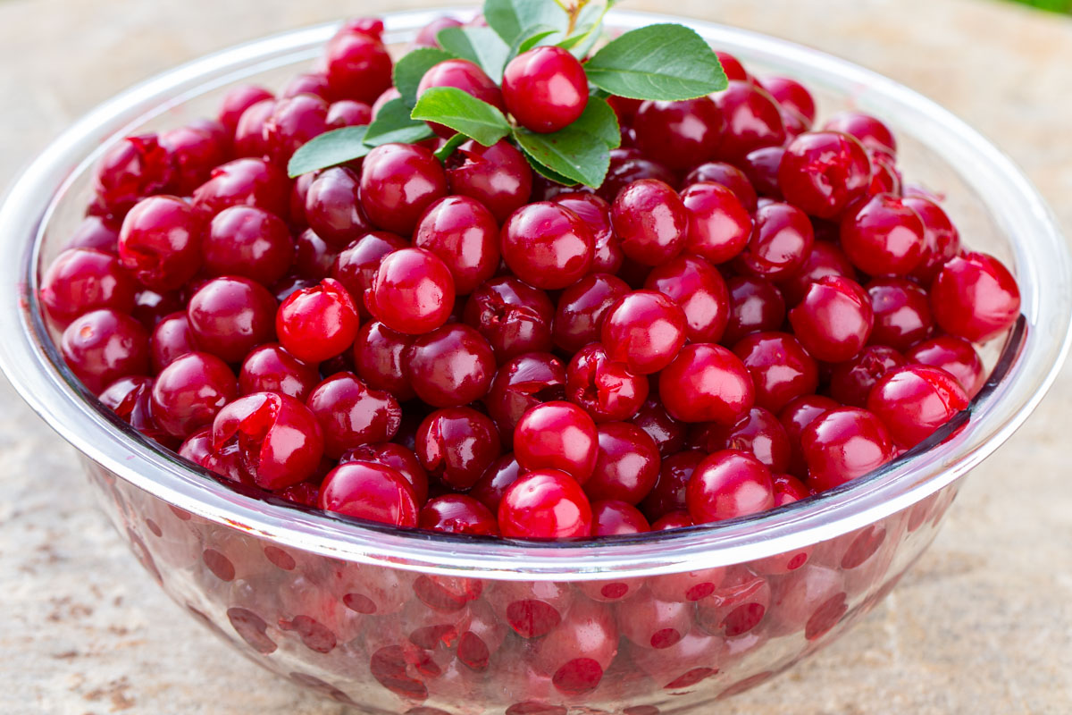 Glass bowl full of pitted cherries.