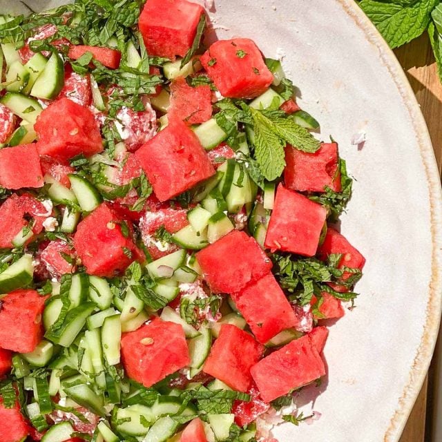 Clay bowl of watermelon, cucumber, mint, and feta cheese salad.