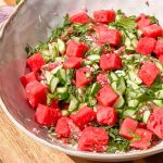 Clay bowl of watermelon, cucumber, mint, and feta cheese salad.