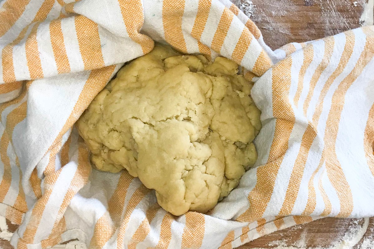Scone dough in a bowl lined with a tea towel.