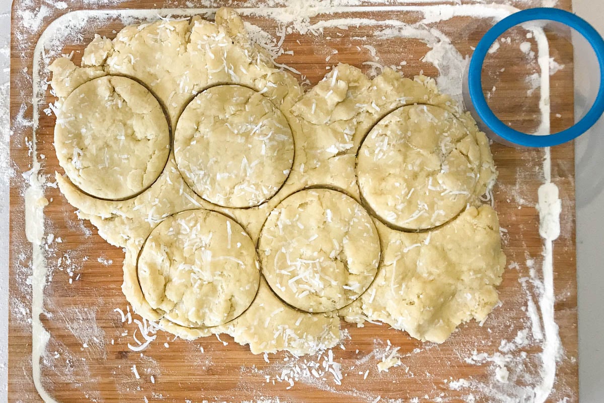 Scone dough cut into circles on wood cutting board.
