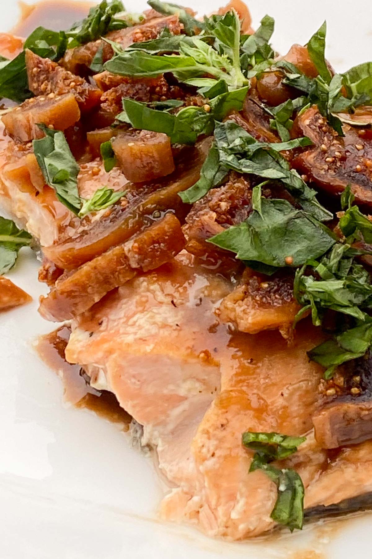 Baked salmon fillet topped with balsamic glaze, sliced figs and fresh herbs.