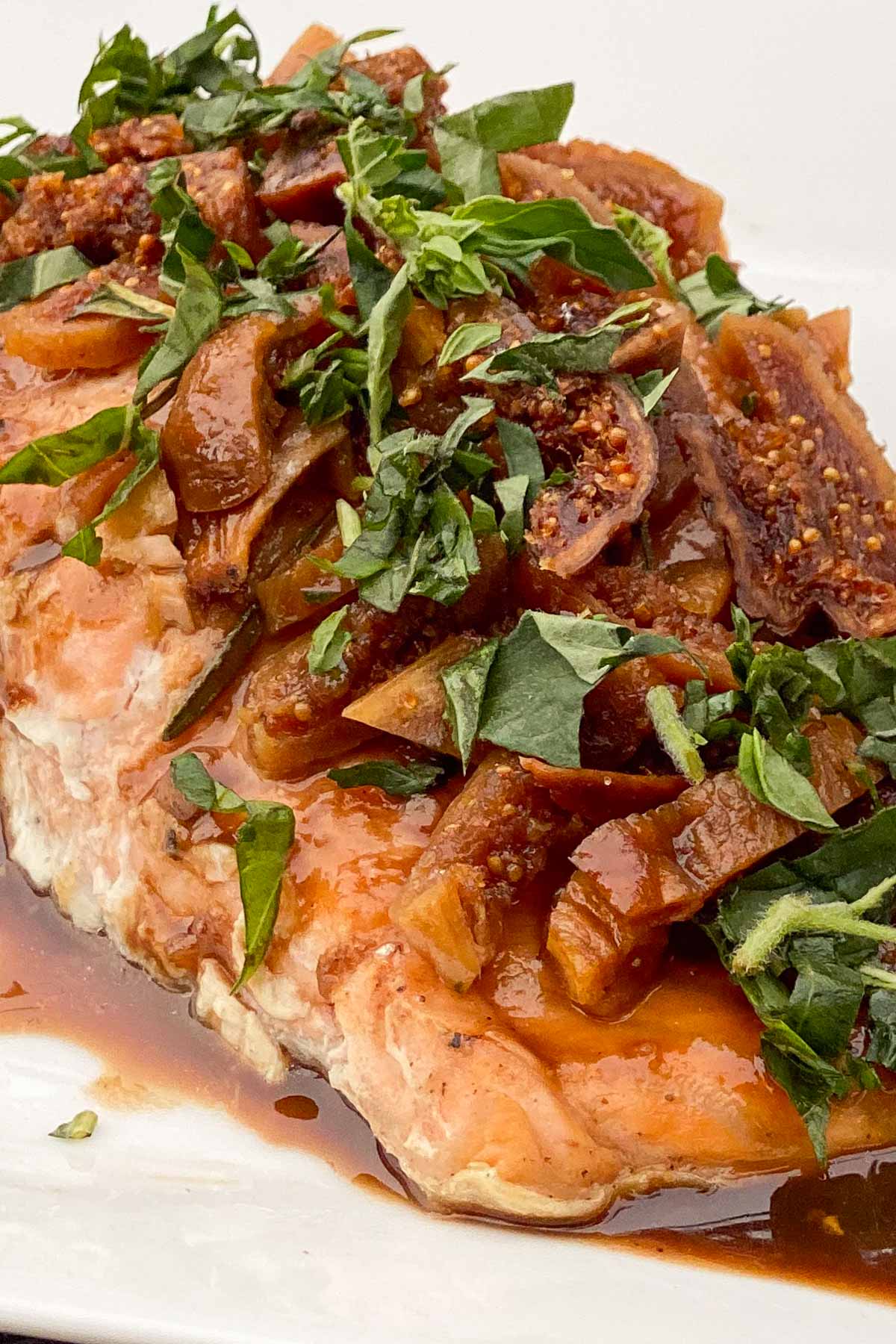 Baked salmon fillet topped with balsamic glaze, sliced figs and fresh herbs.