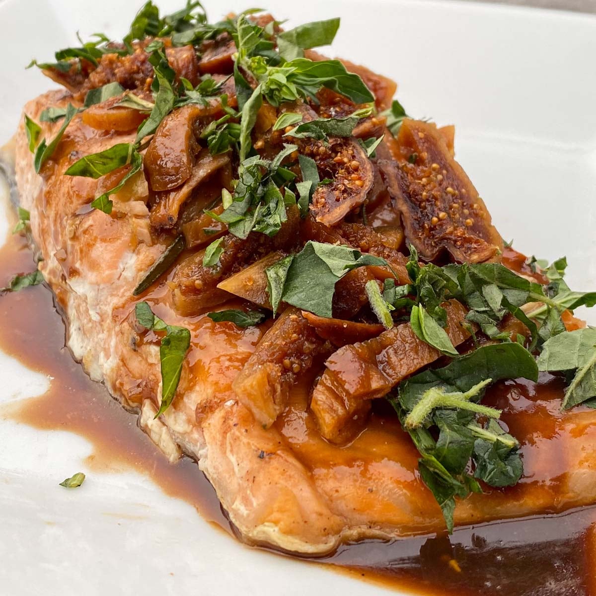 Baked salmon fillet topped with balsamic glaze, sliced figs and fresh herbs.