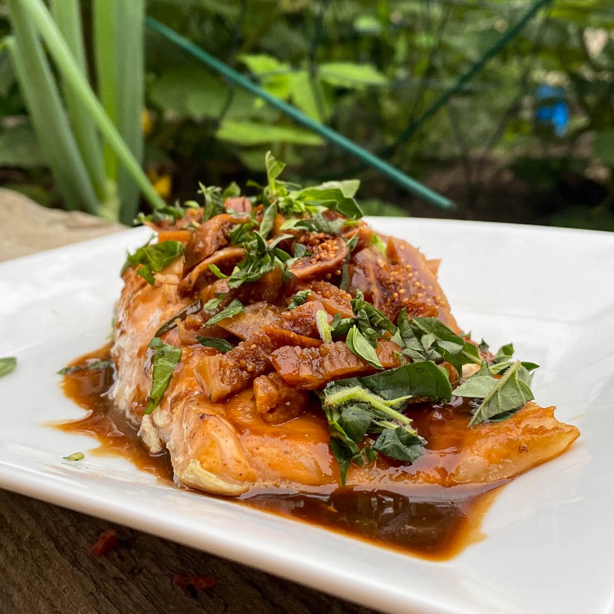 Baked salmon fillet topped with balsamic glaze, sliced figs and fresh herbs.