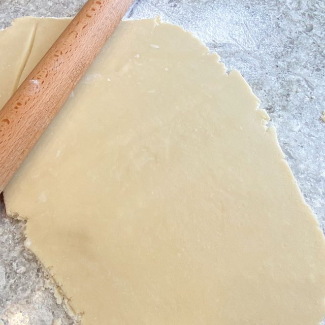 Sugar cookie dough rolled out with rolling pin.