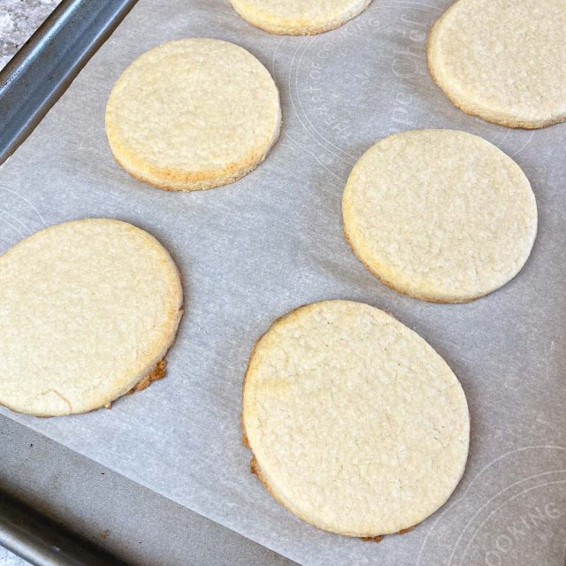 Baked sugar cookies on parchment lined baking sheet.