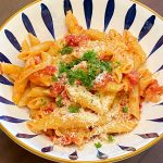 Penne pasta and tomato sauce, garnished with parsley in blue and white decorative bowl.