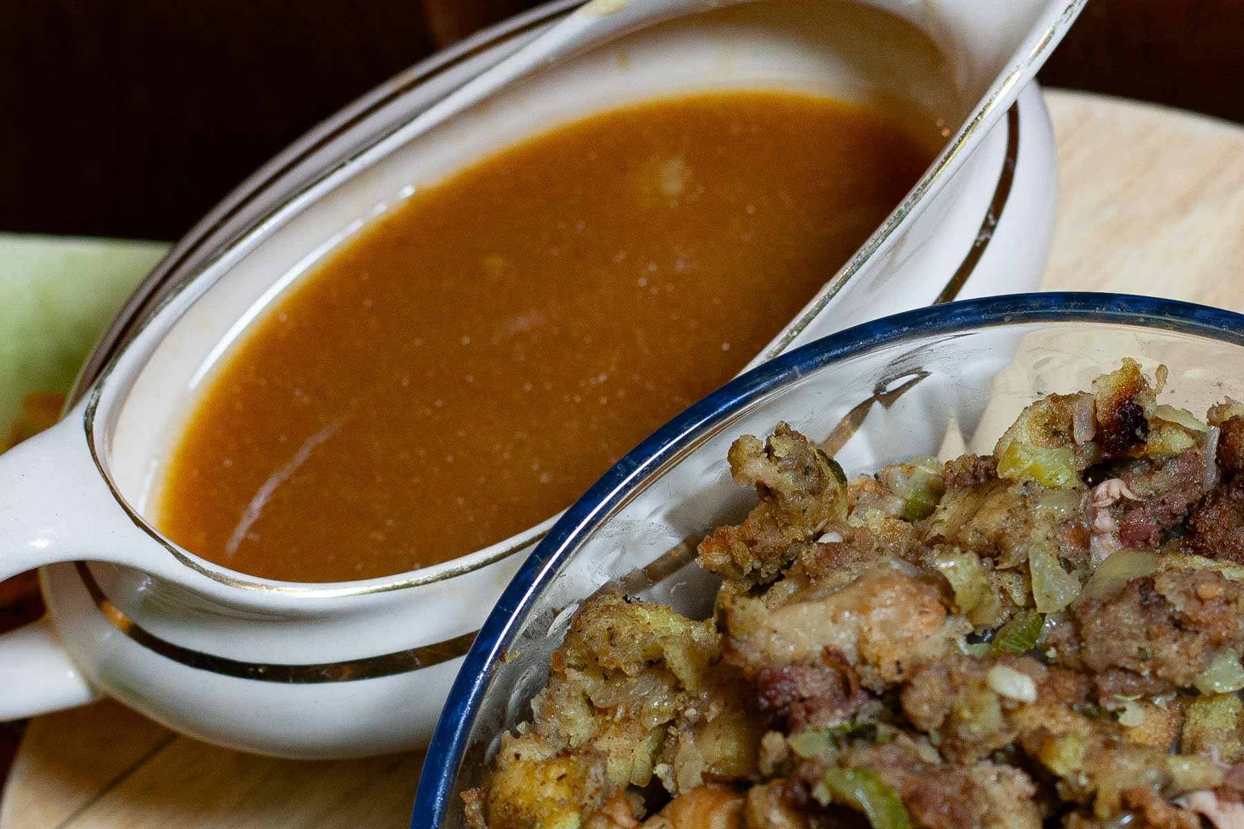 Gravy boat filled with gravy and side bowl of stuffing.