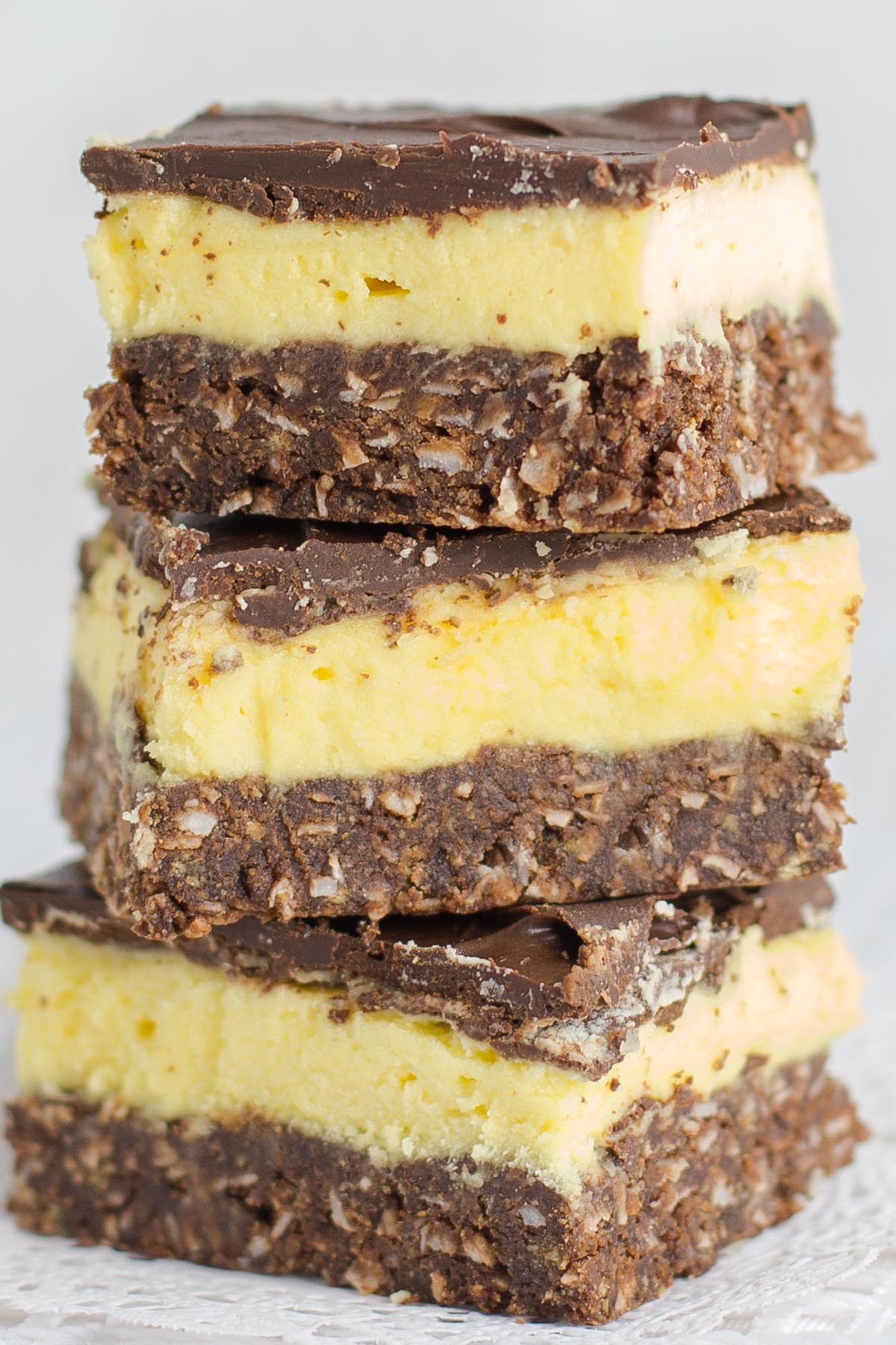 Stack of squares that have layers of chocolate, yellow custard and chocolate coconut crust.