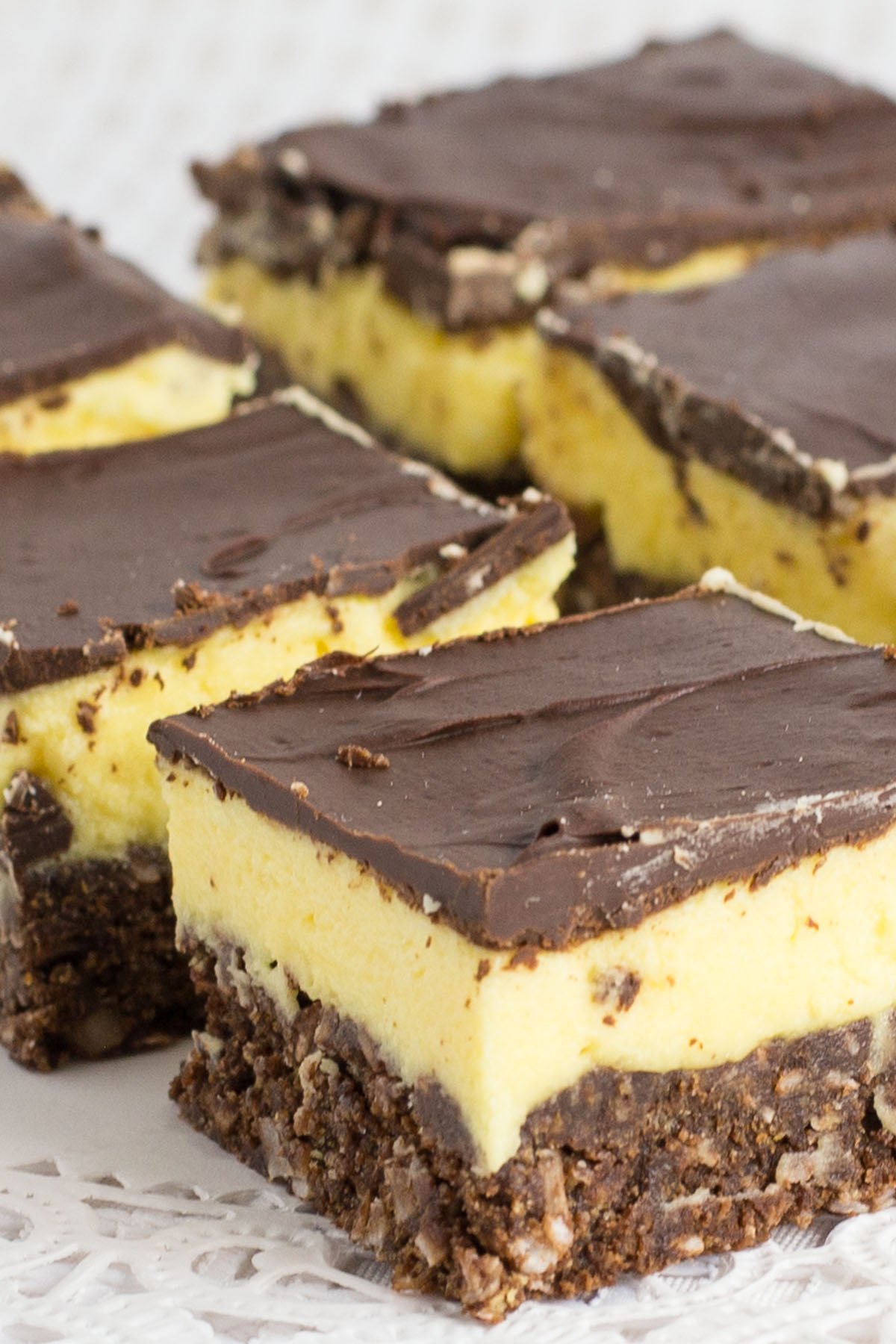 Rows of cut up Nanaimo bars made with layers of chocolate, yellow custard and chocolate coconut.