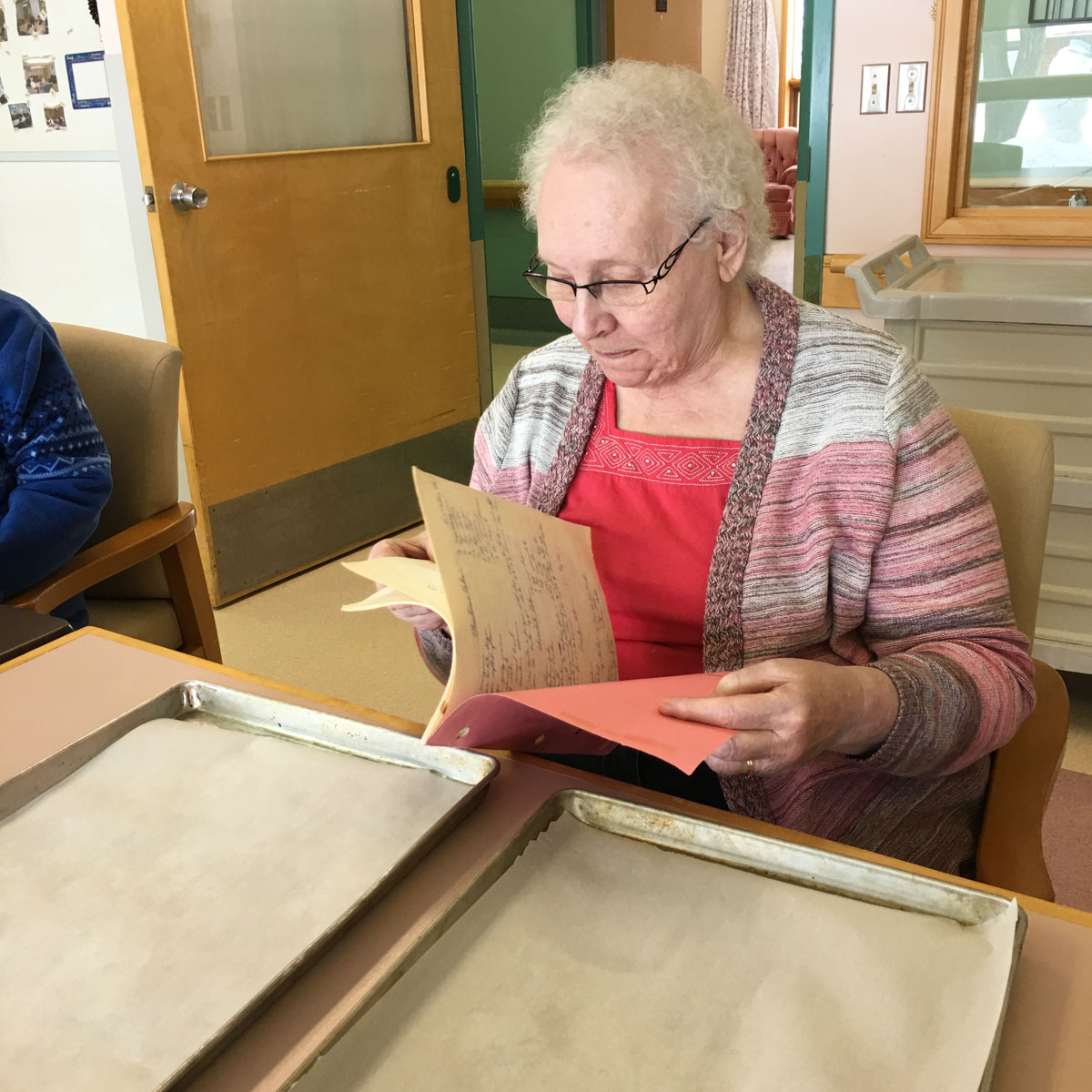 Senior woman looking through her old scribbler recipe book.