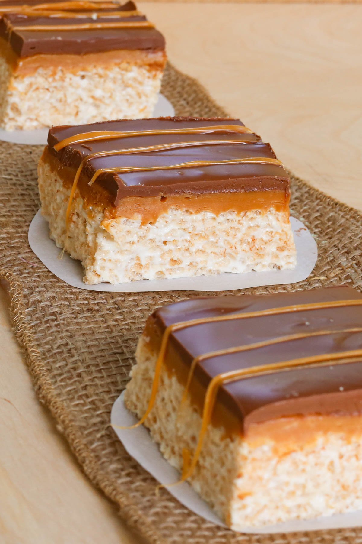 Row of Rice Krispie treats with layers of caramel and chocolate.