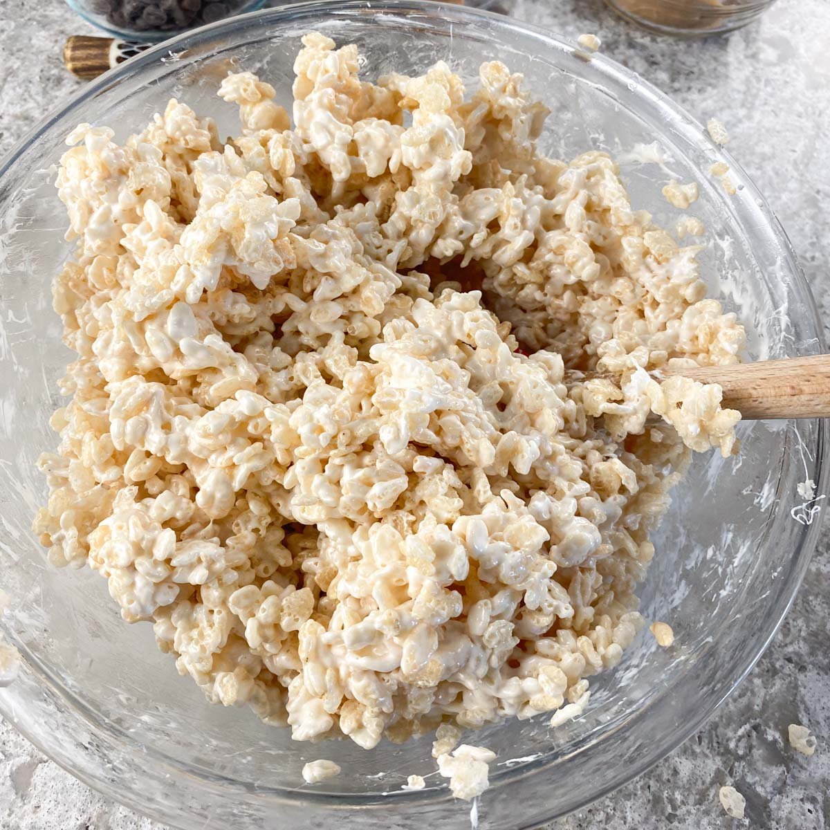 Glass bowl of Rice Krispie cereal and melted marshmallow mixture.