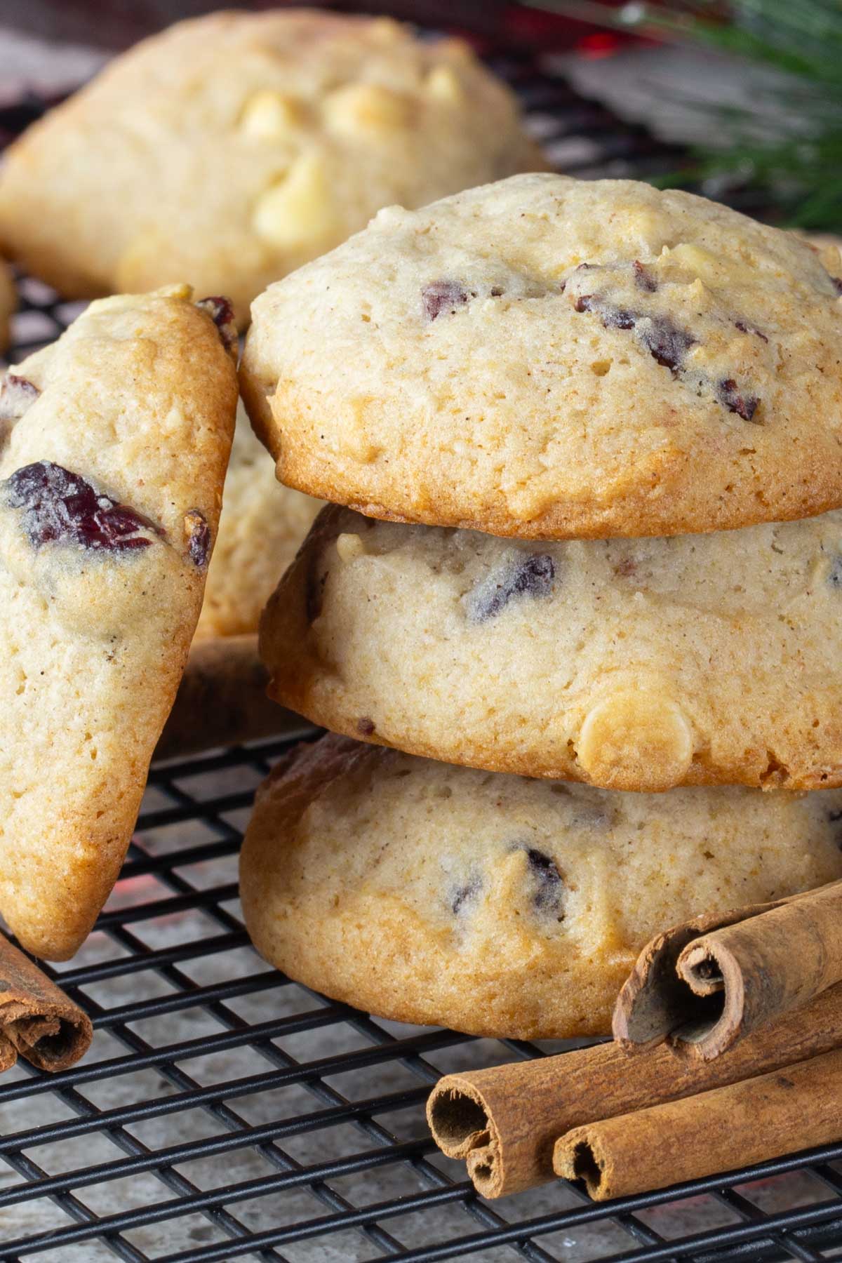 Fluffy cookies with eggnog and cranberries on cooling rack with cinnamon sticks.