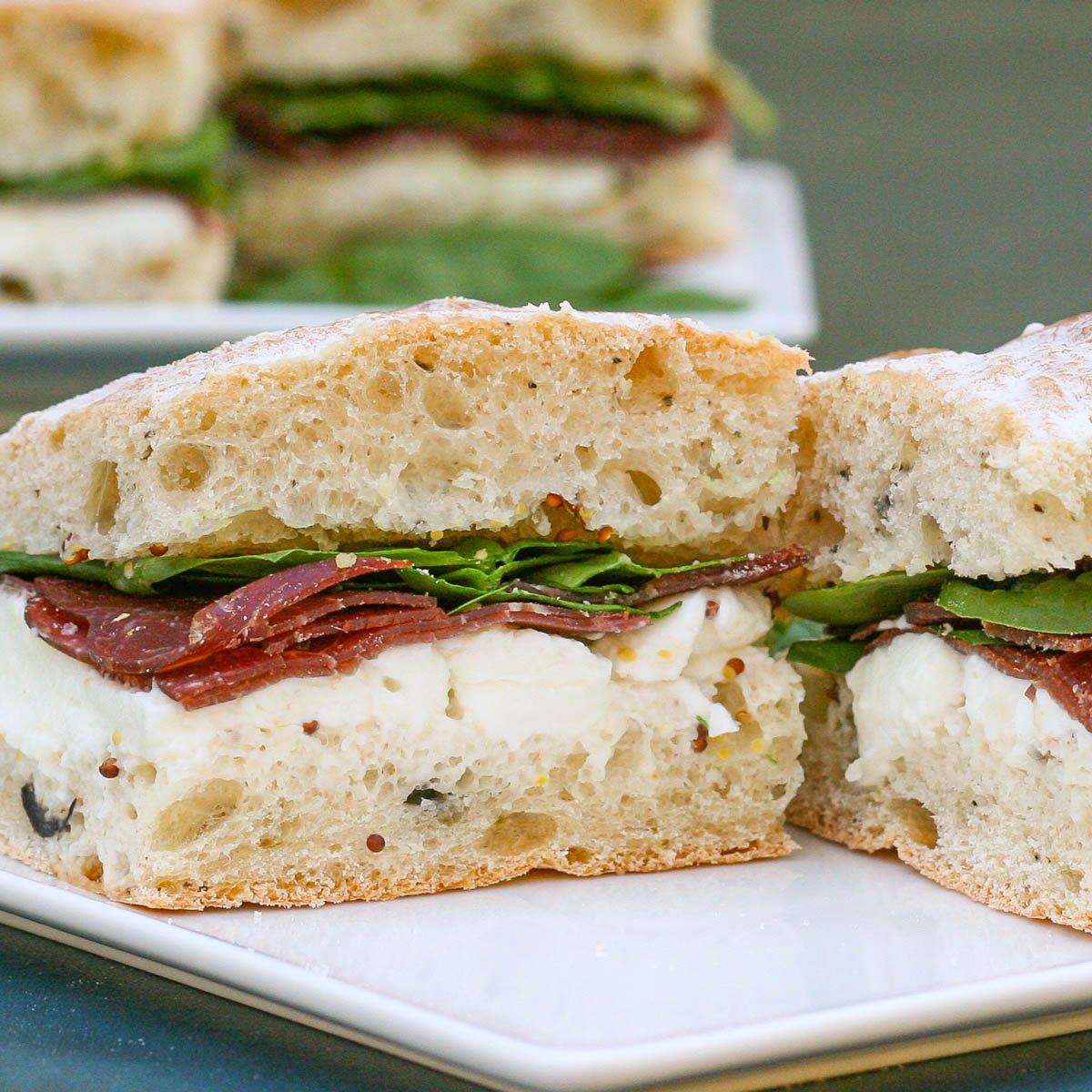 Italian style sandwich with bresaola and mozzarella on a white plate.