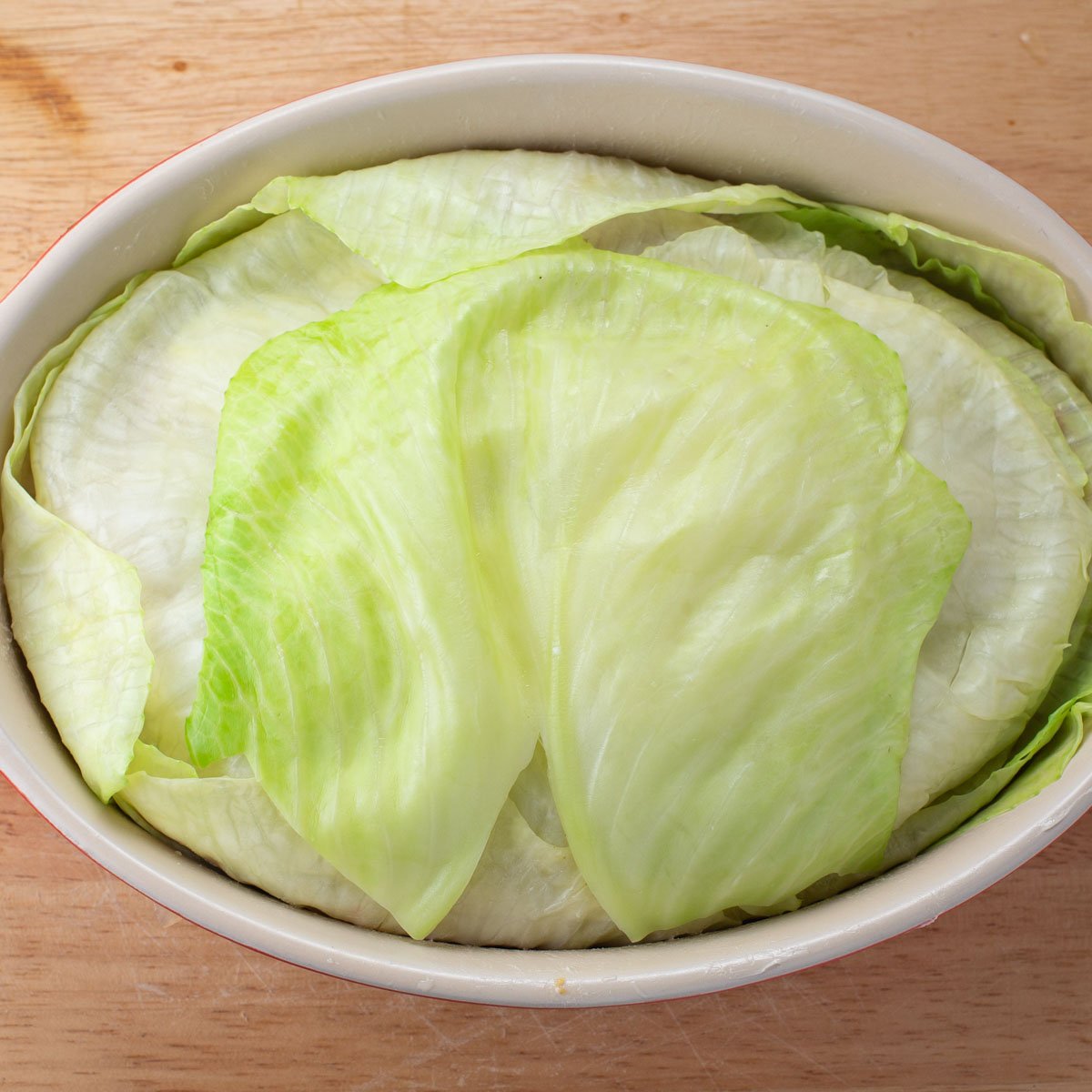 Uncooked casserole dish of layers of cabbage and ground turkey.